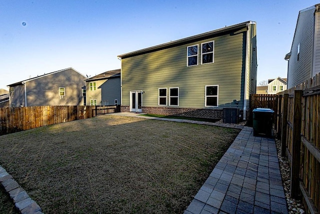 rear view of house featuring brick siding, a fenced backyard, a patio area, and a yard