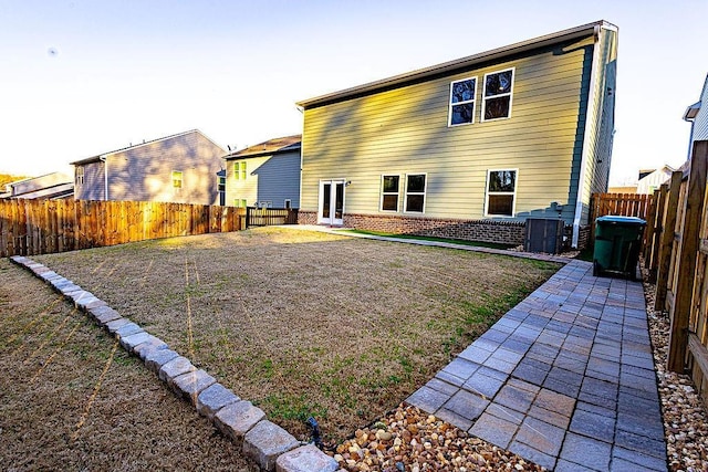 back of property featuring a fenced backyard, a patio, and brick siding