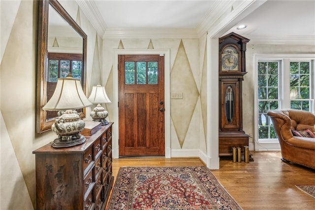 entryway with light wood-type flooring, ornamental molding, and baseboards