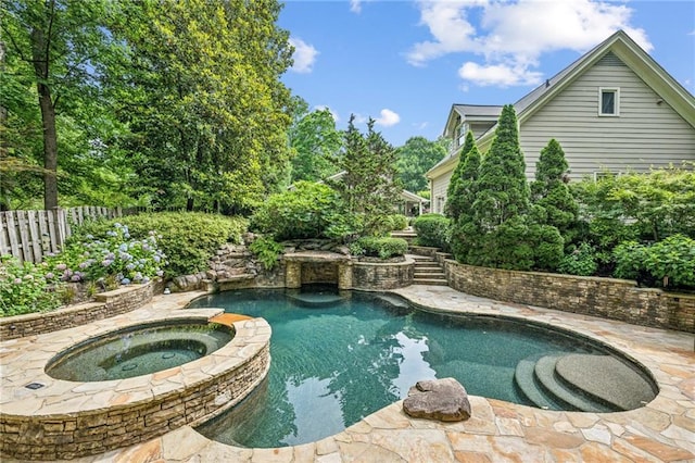 outdoor pool with fence and an in ground hot tub