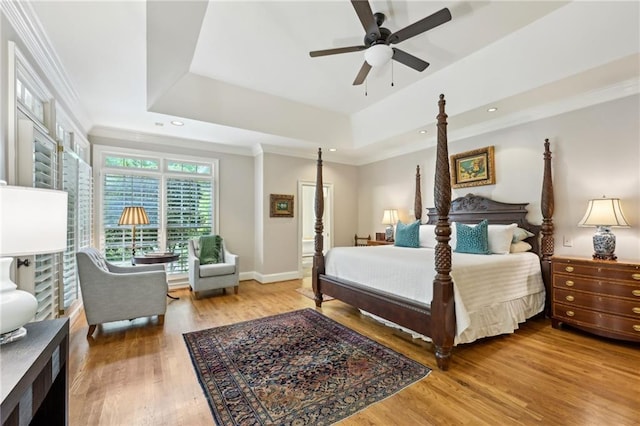 bedroom featuring wood finished floors, a raised ceiling, and crown molding