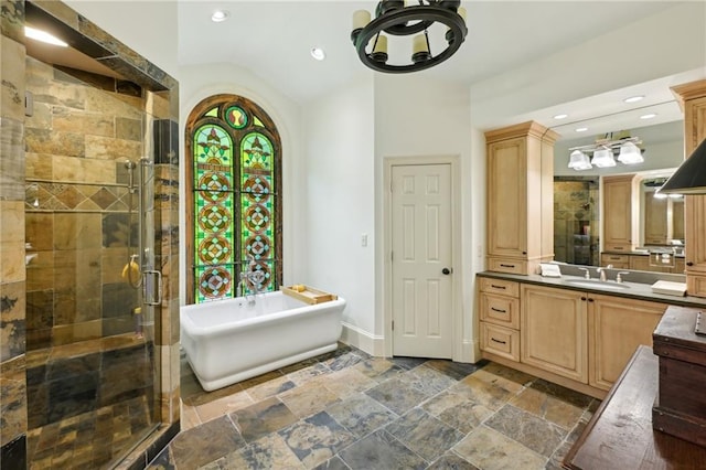 bathroom featuring stone tile flooring, a stall shower, baseboards, vanity, and a freestanding bath