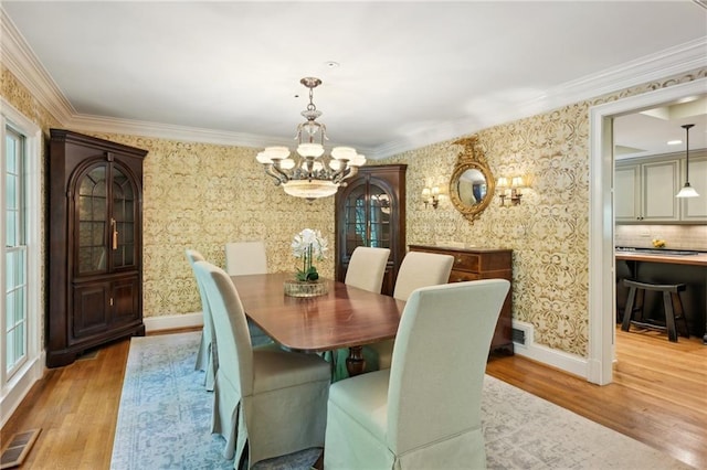 dining space featuring an inviting chandelier, visible vents, light wood finished floors, and wallpapered walls