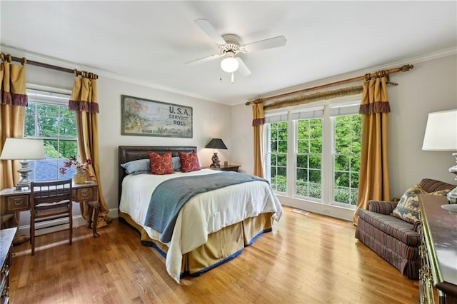 bedroom featuring ornamental molding, a ceiling fan, and light wood-style flooring