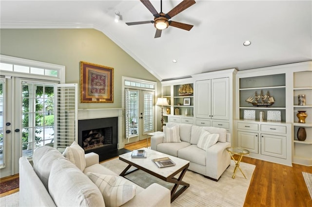 living area with lofted ceiling, a healthy amount of sunlight, a ceiling fan, and light wood finished floors