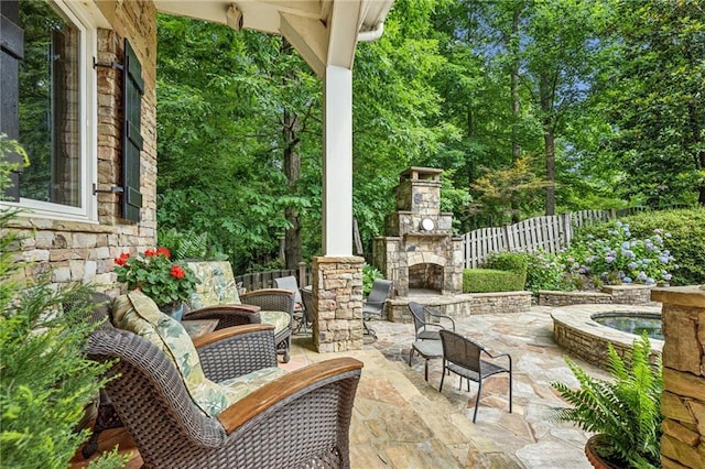 view of patio featuring an outdoor stone fireplace and fence
