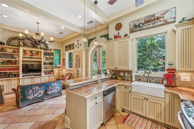 kitchen featuring range, dishwasher, a sink, tile countertops, and cream cabinetry