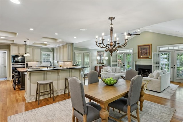 dining space with an inviting chandelier, a healthy amount of sunlight, light wood-type flooring, and a fireplace