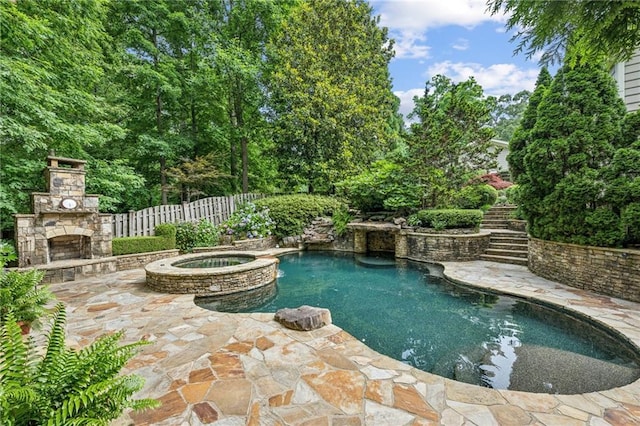 view of swimming pool featuring stairway, fence, a patio, a pool with connected hot tub, and an outdoor stone fireplace