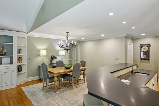 dining area with recessed lighting, ornamental molding, an inviting chandelier, and light wood-style flooring