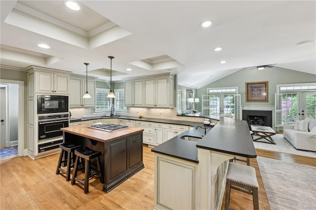 kitchen featuring a kitchen breakfast bar, a sink, black microwave, wooden counters, and wall oven
