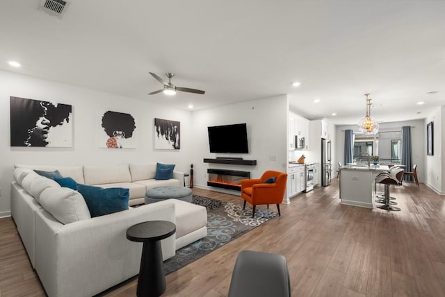 living room with ceiling fan, wood-type flooring, and sink