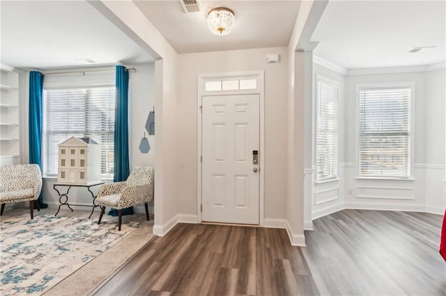 entryway featuring ornamental molding, dark wood-type flooring, and a notable chandelier