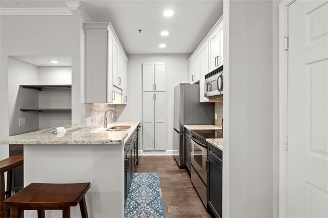 2865 Lenox Rd NE Unit 410, Atlanta, GA 30324 - kitchen with a breakfast bar area, dark wood-type flooring, a sink, appliances with stainless steel finishes, and backsplash