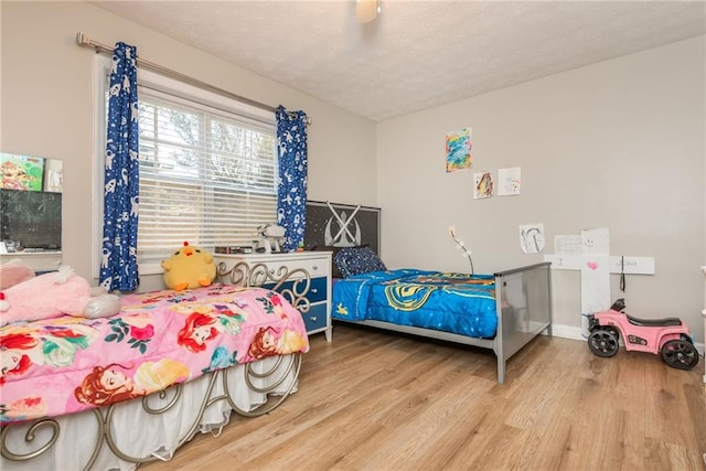 bedroom featuring ceiling fan, wood-type flooring, and a textured ceiling