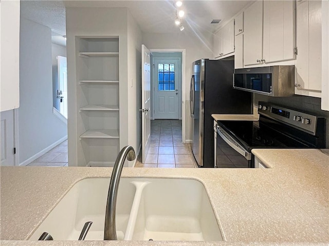 kitchen featuring light tile patterned flooring, built in features, white cabinetry, sink, and stainless steel appliances