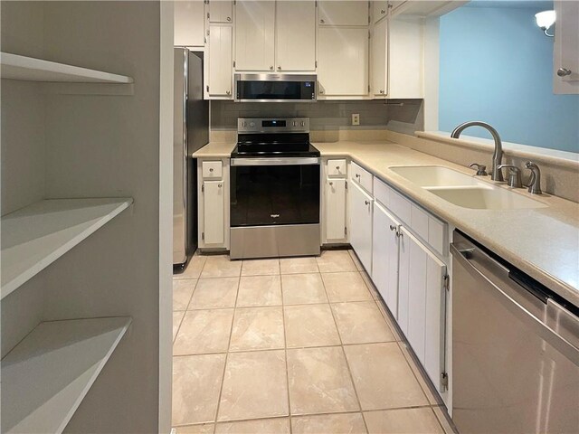 kitchen with light tile patterned floors, appliances with stainless steel finishes, sink, and white cabinets