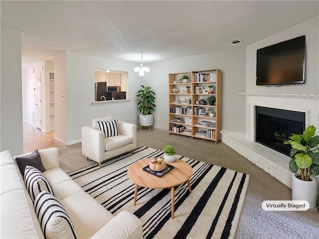 carpeted living room with a brick fireplace, a notable chandelier, and a textured ceiling