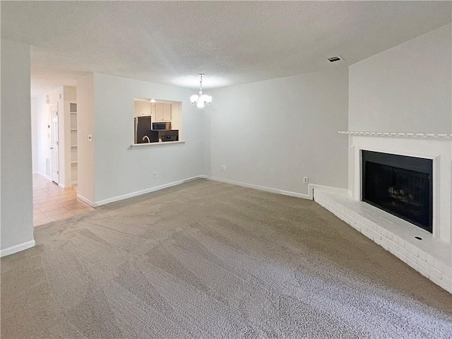 unfurnished living room featuring a brick fireplace, a chandelier, a textured ceiling, and carpet