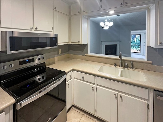 kitchen with tasteful backsplash, sink, white cabinets, light tile patterned floors, and stainless steel appliances