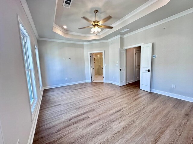 unfurnished bedroom with a tray ceiling, light hardwood / wood-style floors, ceiling fan, and crown molding