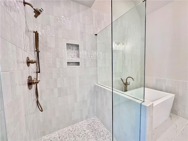 bathroom with shower with separate bathtub and tile walls