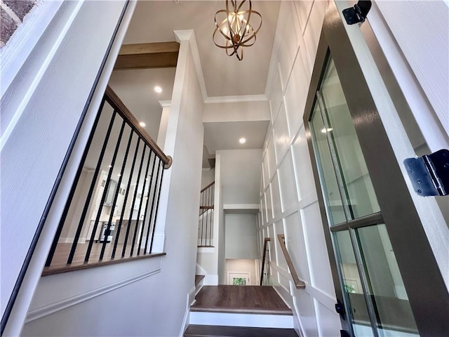 stairway featuring an inviting chandelier, a high ceiling, and ornamental molding