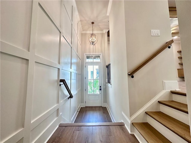 doorway featuring a notable chandelier, ornamental molding, and dark hardwood / wood-style flooring