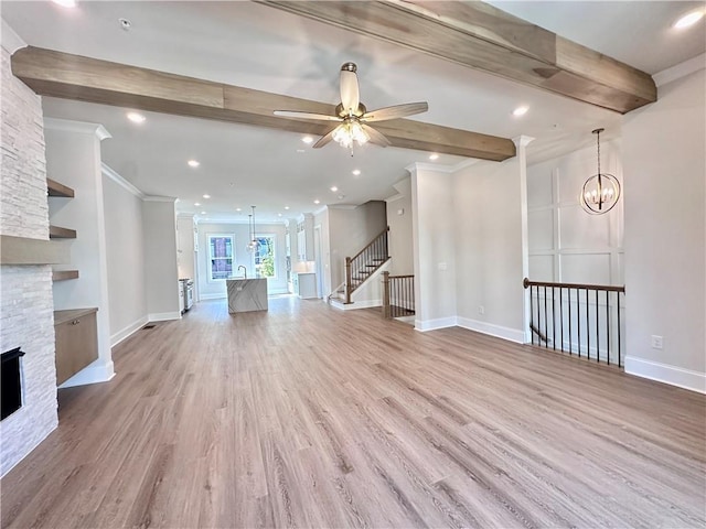 unfurnished living room featuring a stone fireplace, beamed ceiling, light wood-type flooring, and ornamental molding