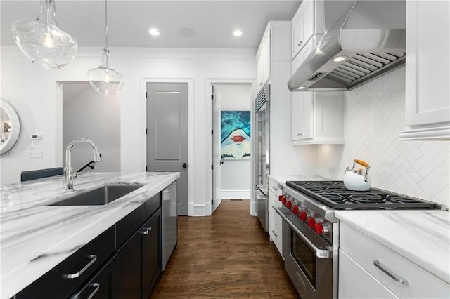 kitchen with high quality appliances, extractor fan, white cabinets, a sink, and recessed lighting