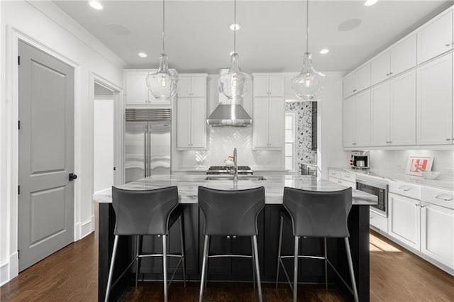 kitchen featuring built in appliances, wall chimney exhaust hood, white cabinetry, recessed lighting, and dark wood-type flooring
