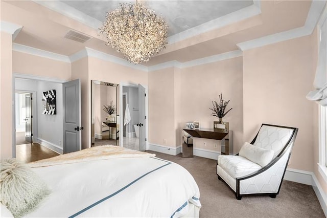 carpeted bedroom with a tray ceiling, a chandelier, baseboards, and ornamental molding