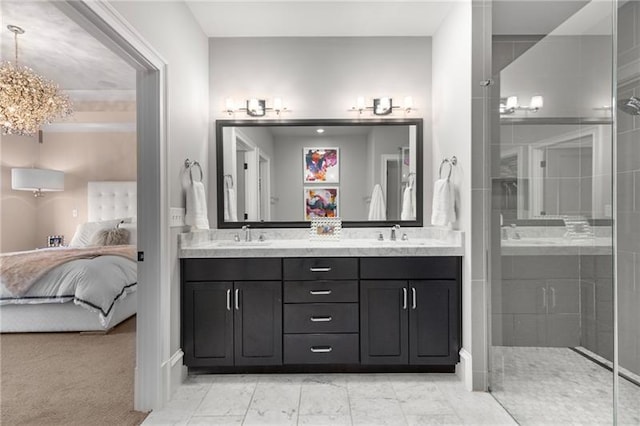 ensuite bathroom featuring a tile shower, double vanity, a chandelier, and baseboards