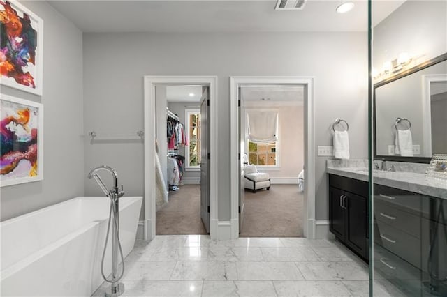 full bath featuring marble finish floor, visible vents, a freestanding bath, vanity, and baseboards