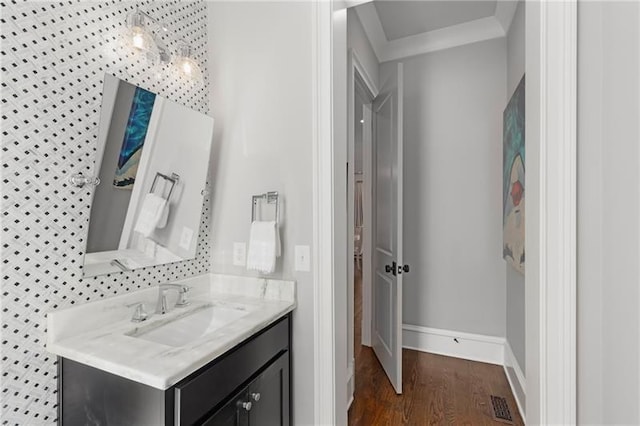 bathroom with crown molding, wood finished floors, vanity, and baseboards