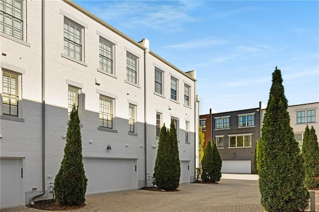 view of building exterior featuring an attached garage and decorative driveway