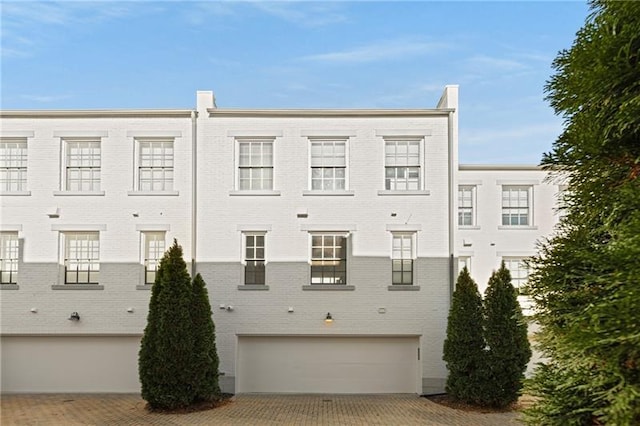 view of building exterior featuring an attached garage and decorative driveway