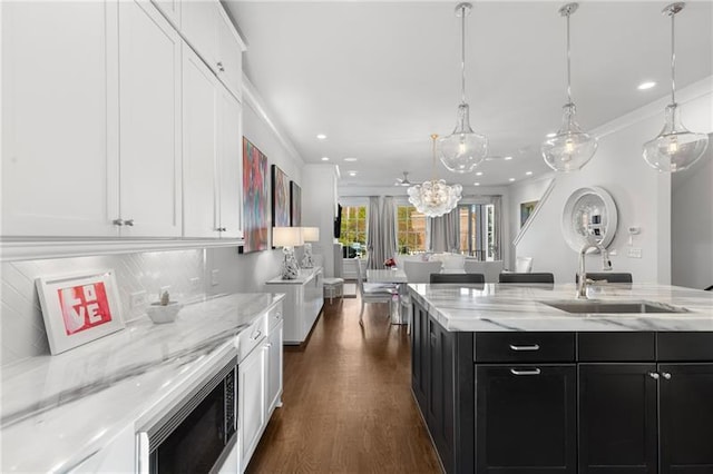 kitchen with a sink, dark cabinets, white cabinets, dark wood finished floors, and built in microwave