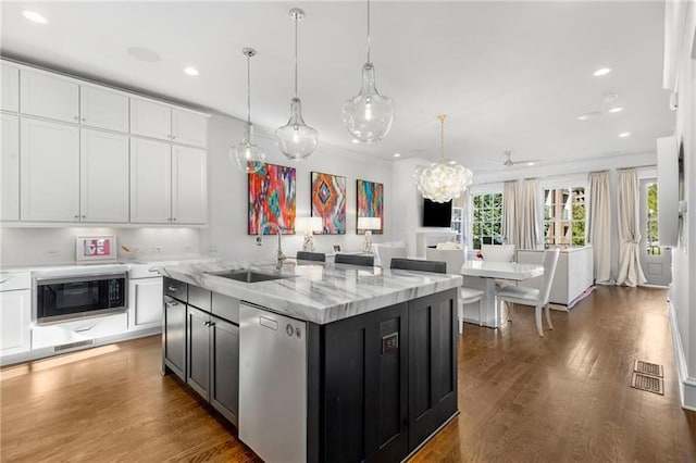 kitchen with white cabinets, a sink, wood finished floors, black microwave, and dishwasher