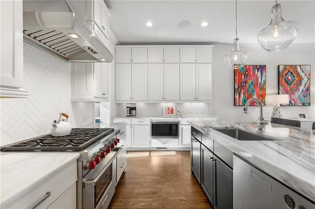 kitchen featuring appliances with stainless steel finishes, range hood, a sink, white cabinetry, and decorative backsplash