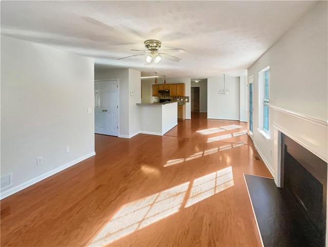 unfurnished living room with hardwood / wood-style floors and ceiling fan with notable chandelier