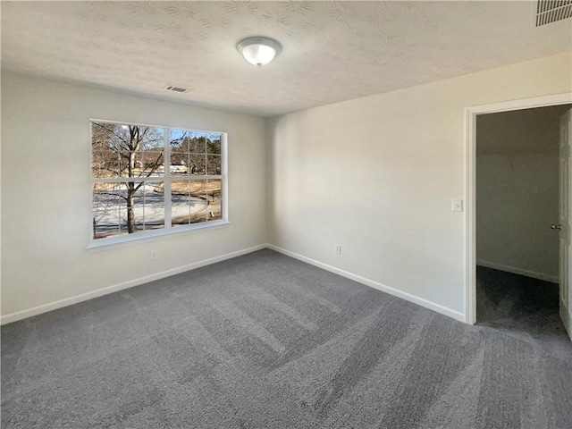 carpeted empty room with a textured ceiling