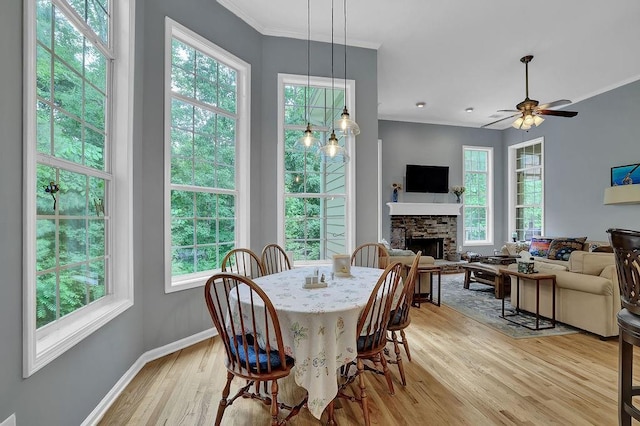 5581 River Valley Way, Flowery Branch, GA 30542 - dining space with a stone fireplace, light wood-type flooring, healthy amount of natural light, baseboards, and ornamental molding