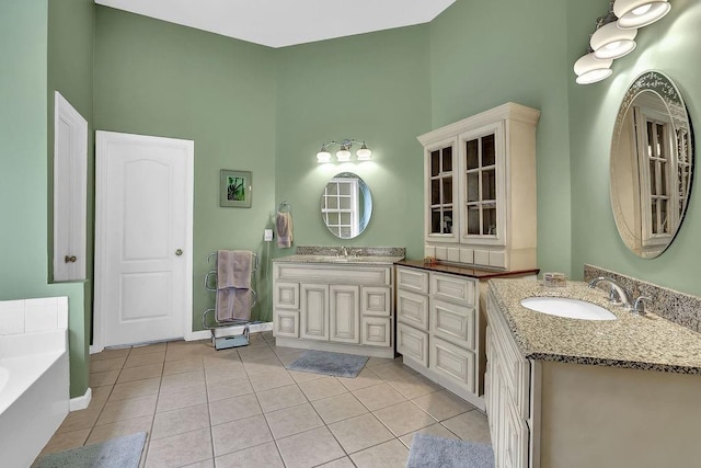5581 River Valley Way, Flowery Branch, GA 30542 - full bathroom featuring tile patterned floors, a garden tub, two vanities, a towering ceiling, and baseboards