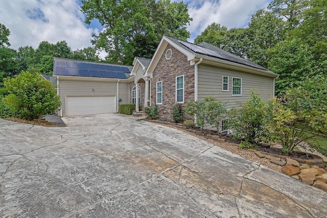 5581 River Valley Way, Flowery Branch, GA 30542 - ranch-style home with roof mounted solar panels, stone siding, concrete driveway, and a garage