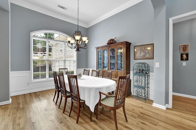 5581 River Valley Way, Flowery Branch, GA 30542 - dining space with light wood-style flooring, a chandelier, crown molding, and wainscoting