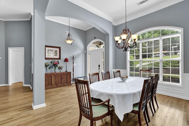 5581 River Valley Way, Flowery Branch, GA 30542 - dining space featuring arched walkways, light wood finished floors, crown molding, a high ceiling, and a chandelier