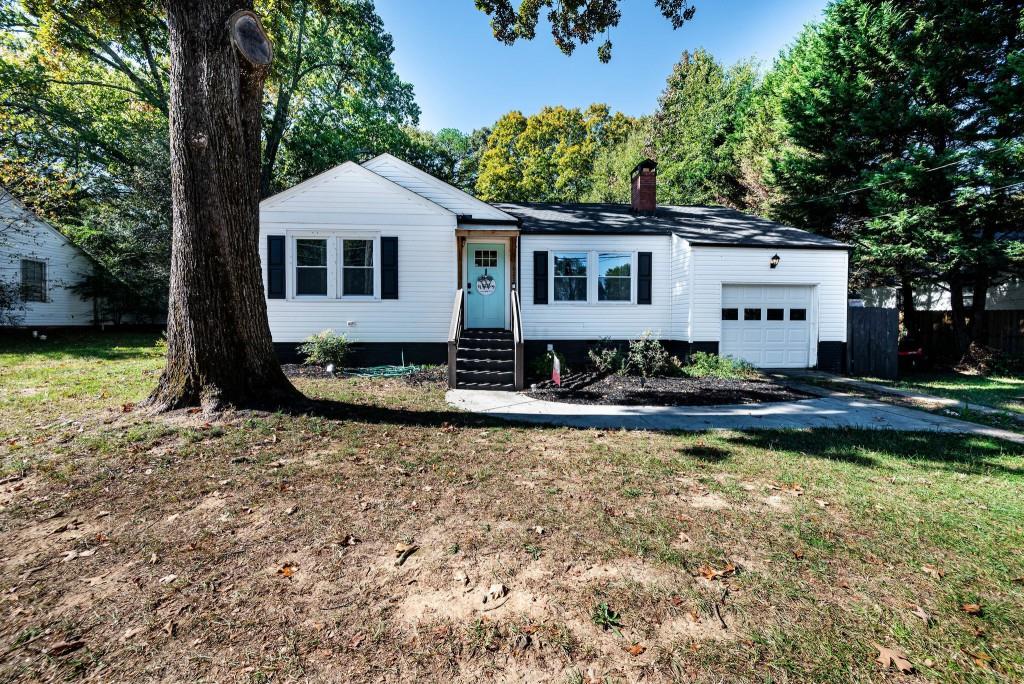 view of front of house with a garage, a chimney, a front yard, and entry steps