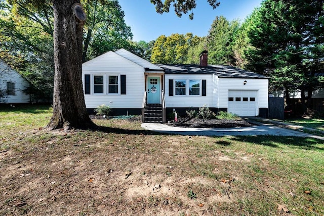 view of front of house with a garage, a chimney, a front yard, and entry steps