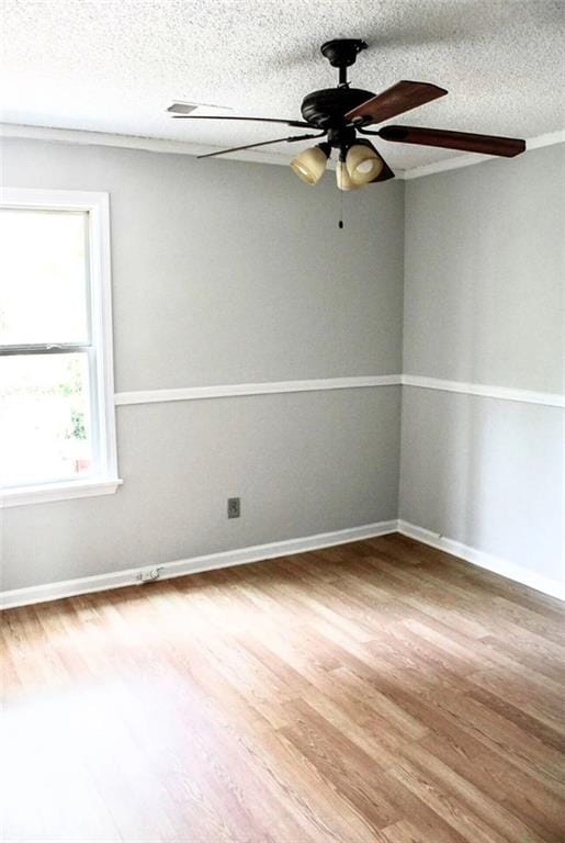 spare room featuring a textured ceiling, baseboards, ceiling fan, and wood finished floors